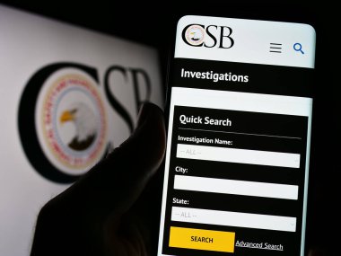 Stuttgart, Almanya - 06-18-2023: Amerikan federal ajansı CSB 'nin web sayfası olan akıllı telefonu logo önünde ekranda tutan kişi. Telefon ekranının sol üst kısmına odaklan.