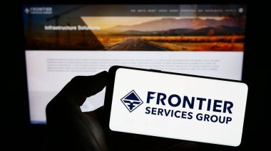 Stuttgart, Almanya - 06-19-2023: İnternet sayfası önünde üzerinde Sınır Hizmetleri Grubu Limited (FSG) logosu bulunan cep telefonu sahibi kişi. Telefon ekranına odaklan.