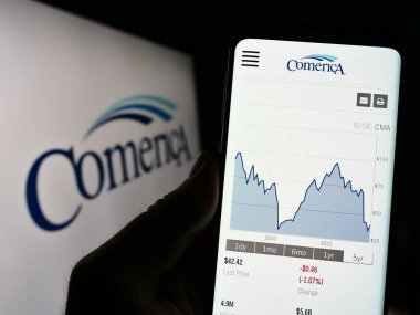 Stuttgart, Almanya - 06-19-2023: ABD 'li finans hizmetleri şirketi Comerica Inc.' in İnternet sayfası ile cep telefonu tutan kişi logo önünde ekranda. Telefon ekranının merkezine odaklan.