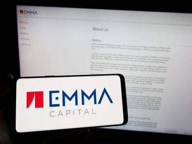 Stuttgart, Almanya - 06-19-2023: Çek yatırım şirketi EMMA Capital 'in logosunu elinde tutan kişi web sitesinin önünde ekranda. Telefon ekranına odaklan.