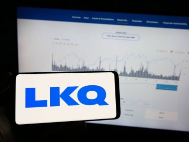 Stuttgart, Almanya - 06-19-2023: Üzerinde Amerikan otomobil parçaları şirketi LKQ Corporation 'ın logosu olan cep telefonu sahibi kişi web sayfasının önünde ekranda. Telefon ekranına odaklan.