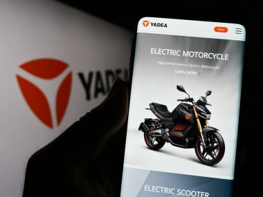 Stuttgart, Almanya - 06-19-2023: Çinli şirket Yadea Group Holding Ltd. 'nin internet sitesi ile cep telefonu tutan kişi logonun önünde ekranda. Telefon ekranının merkezine odaklan.