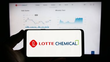 Stuttgart, Germany - 06-19-2023: Person holding mobile phone with logo of Korean company Lotte Chemical Corporation on screen in front of web page. Focus on phone display. clipart