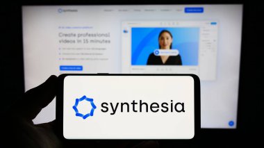 Stuttgart, Almanya - 06-19-2023: İngiliz AI şirketi Synthesia Limited 'in logosuna sahip akıllı telefon sahibi kişi web sitesinin önünde ekranda. Telefon ekranına odaklan.