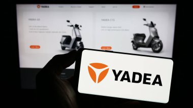 Stuttgart, Almanya - 06-19-2023: Çinli Yadea Group Holding Ltd. şirketinin logosuyla cep telefonu sahibi kişi iş sayfasının önünde ekranda. Telefon ekranına odaklan.