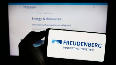 Stuttgart, Almanya - 06-19-2023: Alman firması Freudenberg SE 'nin logosuyla cep telefonu sahibi kişi iş sayfasının önünde ekranda. Telefon ekranına odaklan.