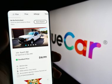 Stuttgart, Almanya - 06-23-2023: ABD otomotiv fiyatlandırma şirketi TrueCar Inc. 'in web sayfası ile akıllı telefonu elinde tutan kişi logolu ekranda. Telefon ekranının merkezine odaklan.