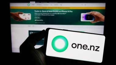 Stuttgart, Almanya - 06-24-2023: İnternet sayfası önünde ekranda One New Zealand Group Limited (One NZ) şirketinin logosunu elinde tutan kişi. Telefon ekranına odaklan.