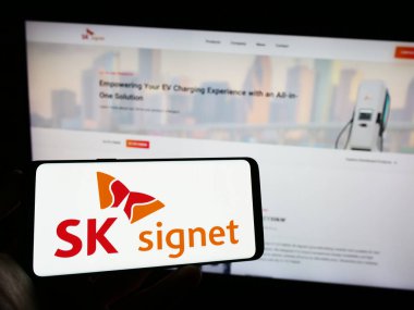 Stuttgart, Almanya - 06-24-2023: Koreli EV şarj şirketi SK Signet 'in logosuna sahip cep telefonu sahibi kişi iş sayfasının önünde ekranda görülüyor. Telefon ekranına odaklan.
