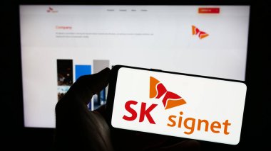 Stuttgart, Almanya - 06-24-2023: Koreli EV şarj şirketi SK Signet 'in logosuna sahip cep telefonu sahibi kişi iş sayfasının önünde ekranda görülüyor. Telefon ekranına odaklan.