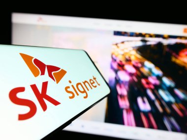Stuttgart, Almanya - 06-24-2023: Koreli EV şarj şirketi SK Signet 'in logosunu taşıyan cep telefonu iş sitesinin önünde ekranda. Telefon ekranının merkez soluna odaklan.