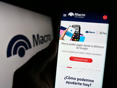 Stuttgart, Almanya - 06-24-2023: Arjantinli finans şirketi Banco Macro SA 'nın web sitesi ile birlikte logo önünde cep telefonu tutan kişi. Telefon ekranının merkezine odaklan.