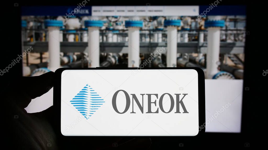 Stuttgart, Germany - 06-18-2023: Person holding cellphone with logo of US natural gas company Oneok Inc. on screen in front of business webpage. Focus on phone display.