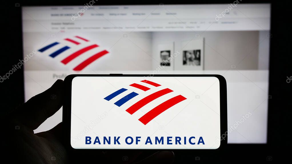 Stuttgart, Germany - 06-24-2023: Person holding smartphone with logo of US company Bank of America Corporation on screen in front of website. Focus on phone display.