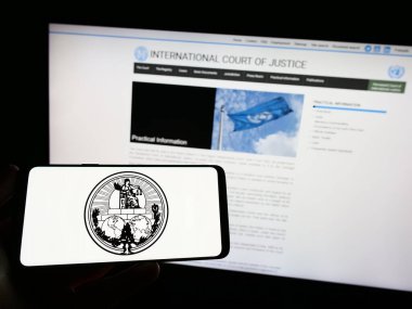 Stuttgart, Germany - 04-23-2023: Person holding smartphone with logo of the International Court of Justice (ICJ) on screen in front of website. Focus on phone display. clipart