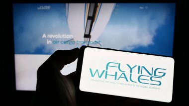 Stuttgart, Almanya - 04-24-2023: Fransız hava gemisi şirketi Flying Whales 'in logosunun bulunduğu cep telefonu sahibi kişi iş sayfasının önünde ekranda. Telefon ekranına odaklan.