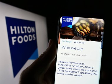 Stuttgart, Almanya - 04-25-2023: İngiliz firması Hilton Food Group plc 'in web sayfası olan cep telefonu logosu önünde ekranda. Telefon ekranının merkezine odaklan.