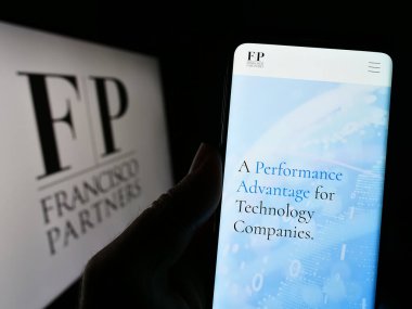 Stuttgart, Almanya - 04-26-2023: ABD 'li şirket Francisco Partners Management L.P.' nin web sitesi ile cep telefonu tutan kişi logolu ekranda. Telefon ekranının merkezine odaklan.