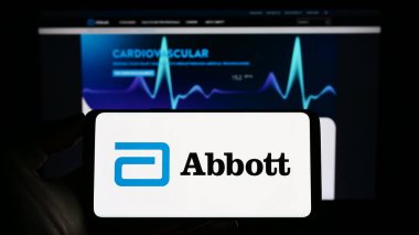 Stuttgart, Almanya - 04-26-2023: ABD 'li sağlık şirketi Abbott Laboratories' in logosuna sahip akıllı telefon sahibi kişi web sitesinin önünde ekranda. Telefon ekranına odaklan.