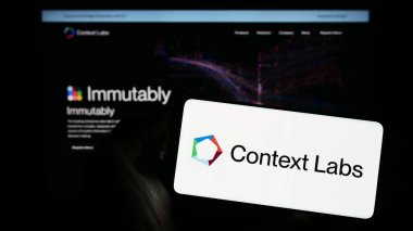 Stuttgart, Germany - 04-26-2023: Person holding mobile phone with logo of Dutch blockchain company Context Labs B.V. (CXL) on screen in front of web page. Focus on phone display. clipart