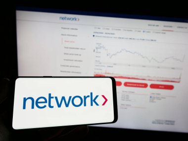Stuttgart, Almanya - 04-26-2023: Network International Holding plc şirketinin logosuna sahip cep telefonu sahibi kişi web sayfasının önünde ekranda. Telefon ekranına odaklan.