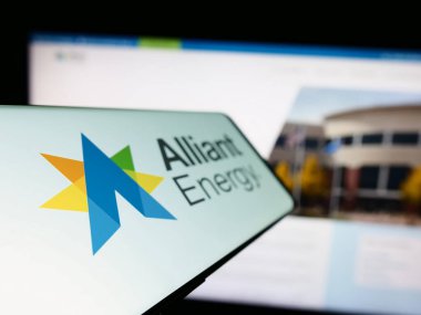 Stuttgart, Almanya - 04-26-2023: Amerikan Alliant Energy Corporation şirketinin logosunun yer aldığı cep telefonu iş sitesinin önünde ekranda. Telefon ekranının soluna odaklan.