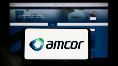 Stuttgart, Almanya - 04-27-2023: Amcor plc ambalaj şirketinin logosuyla cep telefonu sahibi kişi iş sayfasının önünde ekranda. Telefon ekranına odaklan.