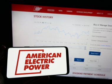 Stuttgart, Almanya - 04-27-2023: Web sayfası önünde üzerinde American Electric Power Inc. (AEP) logosu olan cep telefonu sahibi kişi. Telefon ekranına odaklan.