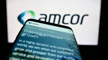 Stuttgart, Almanya - 04-27-2023: Cep telefonu ambalaj şirketi Amcor plc 'nin web sayfası iş logosu önünde ekranda. Telefon ekranının sol üst kısmına odaklan.