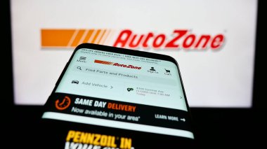 Stuttgart, Germany - 04-28-2023: Mobile phone with webpage of US automotive parts company AutoZone Inc. on screen in front of business logo. Focus on top-left of phone display. clipart