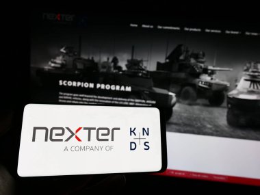Stuttgart, Almanya - 04-28-2023: Fransız savunma şirketi Nexter SA 'nın logosuyla cep telefonu sahibi kişi iş sayfasının önünde ekranda. Telefon ekranına odaklan.