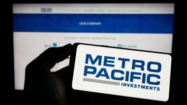 Stuttgart, Almanya - 04-28-2023: Metro Pacific Investments Corporation (MPIC) logosuna sahip cep telefonu web sayfası önünde ekranda. Telefon ekranına odaklan.