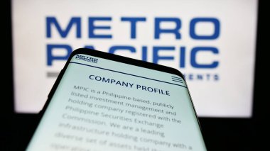 Stuttgart, Almanya - 04-28-2023: Metro Pacific Investments Corporation (MPIC) web sitesi ile birlikte iş logosu önünde cep telefonu. Telefon ekranının sol üst kısmına odaklan.
