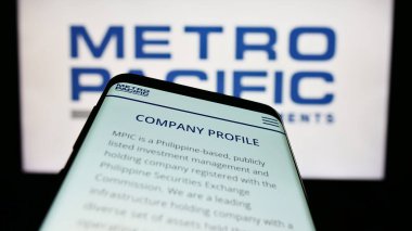 Stuttgart, Germany - 04-28-2023: Mobile phone with website of Metro Pacific Investments Corporation (MPIC) on screen in front of business logo. Focus on top-left of phone display. clipart