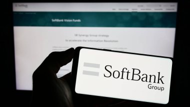 Stuttgart, Almanya - 06-16-2024: Japon yatırım şirketi SoftBank Group Corp 'un logosunu elinde tutan kişi web sitesinin önünde ekranda. Telefon ekranına odaklan.