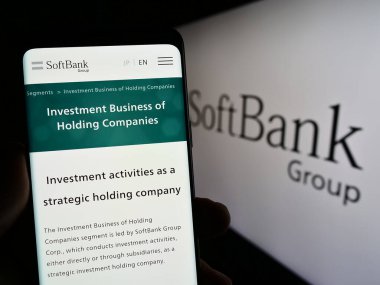 Stuttgart, Almanya - 06-16-2024: Japon yatırım şirketi SoftBank Group Corp. 'un internet sayfası ile cep telefonu tutan kişi logolu ekranda. Telefon ekranının merkezine odaklan.