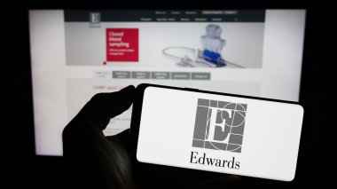 Stuttgart, Almanya - 06-16-2024: ABD 'li Edwards Lifesciences Corporation şirketinin logosuyla cep telefonu sahibi kişi iş sayfası önünde ekranda. Telefon ekranına odaklan.