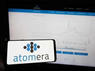 Stuttgart, Almanya - 06-16-2024: Web sayfasının önünde ekranda Amerikan yarı iletken şirketi Atomera Inc. 'in logosunun bulunduğu cep telefonu sahibi kişi. Telefon ekranına odaklan.