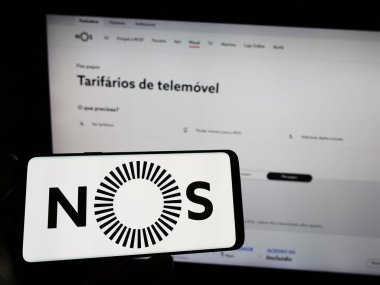 Stuttgart, Almanya - 06-16-2024: Telekomünikasyon şirketi NOS SGPS SA 'nın logosunu taşıyan cep telefonu sahibi iş sayfası önünde ekranda. Telefon ekranına odaklan.