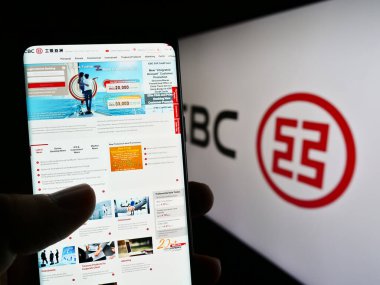 Stuttgart, Almanya - 06-17-2023: Çinli finans hizmetleri şirketi ICBC 'nin internet sitesiyle birlikte logo önünde cep telefonu tutan kişi. Telefon ekranının merkezine odaklan.