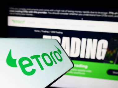 Stuttgart, Almanya - 06-17-2023: İsrailli sosyal ticaret şirketi eToro 'nun logosuna sahip akıllı telefon iş dünyasının web sitesinin önünde ekranda. Telefon ekranının merkezine odaklan.