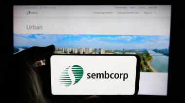 Stuttgart, Almanya - 01-03-2024: Singapur şirketi Sembcorp Industries Ltd. 'nin logosunu taşıyan kişi iş sayfasının önünde ekranda. Telefon ekranına odaklan.
