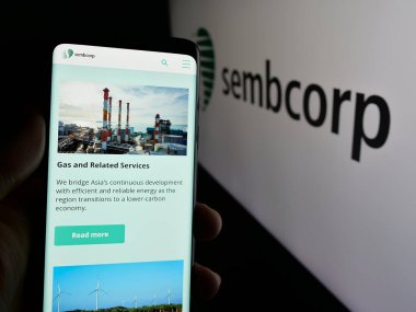 Stuttgart, Almanya - 01-03-2024: Singapur şirketi Sembcorp Industries Ltd. 'nin web sayfası ile cep telefonu tutan kişi logolu ekranda. Telefon ekranının merkezine odaklan.