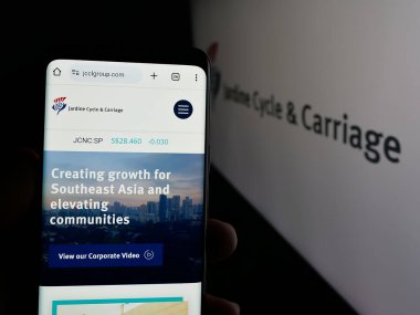 Stuttgart, Almanya - 01-03-2024: Singapur şirketi Jardine Cycle Carriage Limited 'in web sayfası ile akıllı telefon sahibi kişi logolu ekranda. Telefon ekranının merkezine odaklan.