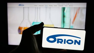 Stuttgart, Almanya - 01-03-2024: Fin ilaç şirketi Orion Oyj 'un logosunun bulunduğu cep telefonu sahibi kişi iş sayfasının önünde ekranda. Telefon ekranına odaklan.