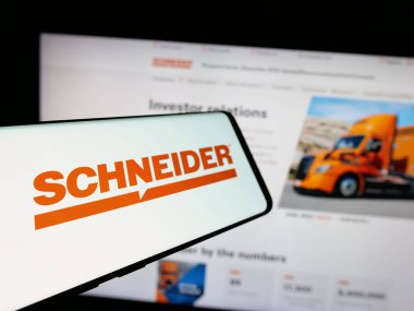 Stuttgart, Germany - 01-07-2024: Cellphone with logo of American logistics company Schneider National Inc. on screen in front of website. Focus on center-left of phone display. clipart