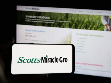 Stuttgart, Almanya - 01-07-2024: ABD 'li işletme logosu olan akıllı telefon sahibi kişi The Scotts Miracle-Gro Company web sitesinin önünde ekranda. Telefon ekranına odaklan.
