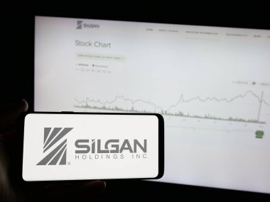 Stuttgart, Almanya - 01-08-2024: İnternet sitesi önünde ekranda ABD 'li ambalaj şirketi Silgan Holding Inc.' nin logosuna sahip akıllı telefonu tutan kişi. Telefon ekranına odaklan.