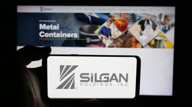 Stuttgart, Almanya - 01-08-2024: ABD 'li ambalaj şirketi Silgan Holding Inc.' nin logosuyla cep telefonu sahibi kişi iş sayfasının önünde ekranda. Telefon ekranına odaklan.