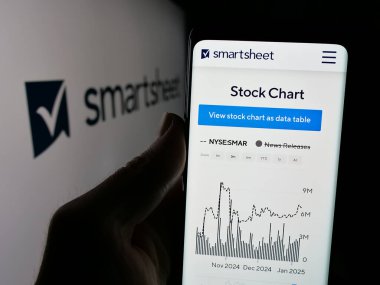 Stuttgart, Almanya - 01-08-2024: ABD 'li işbirliği yazılım şirketi Smartsheet Inc.' in web sayfası ile cep telefonu tutan kişi logolu ekranda. Telefon ekranının merkezine odaklan.